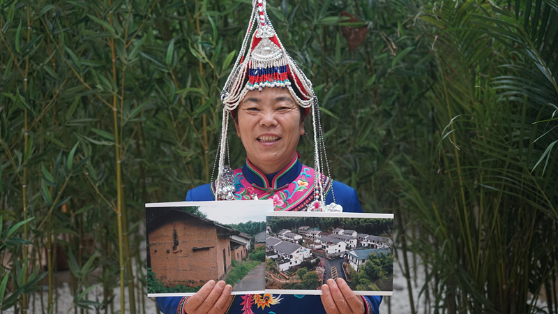 全国人大代表、江西省资溪县新月畲族村党支部第一书记兰念瑛拿着两张对比照片。